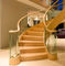 La escalera curvada moderna revestida del grano de madera fácil instala con la verja de cristal